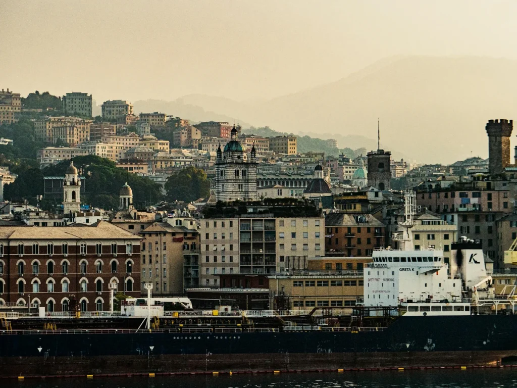 Navi cargo nel porto di Genova con il centro storico medievale e le torri sullo sfondo
