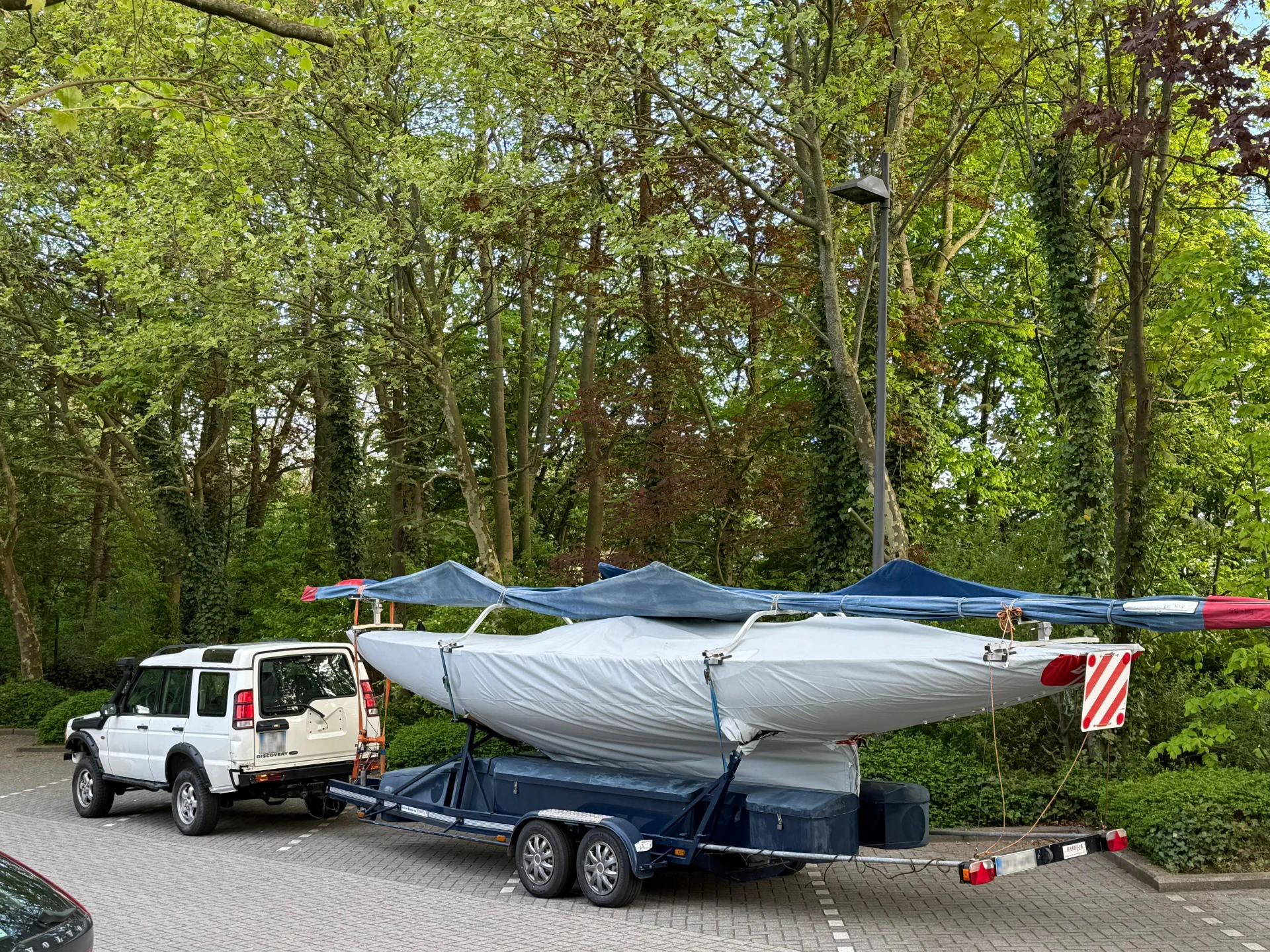 Land Rover Discovery con due derive a vela consegnate in un parcheggio alberato nel Nord Europa